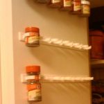 Great Kitchen Storage Ideas—Use a mop holder to store spices on the inside of a cabinet door.
